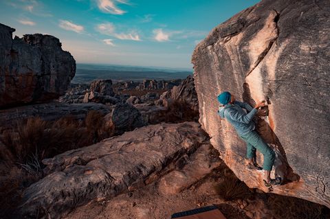 A climber on a sandstone wall at Rocklands with the Cederberg plateau stretching to the horizon behind