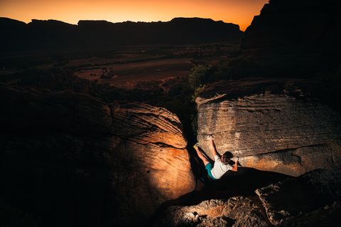 A boulderer on a sandstone arete at Rocklands at sunset, high above the Cederberg valley floor