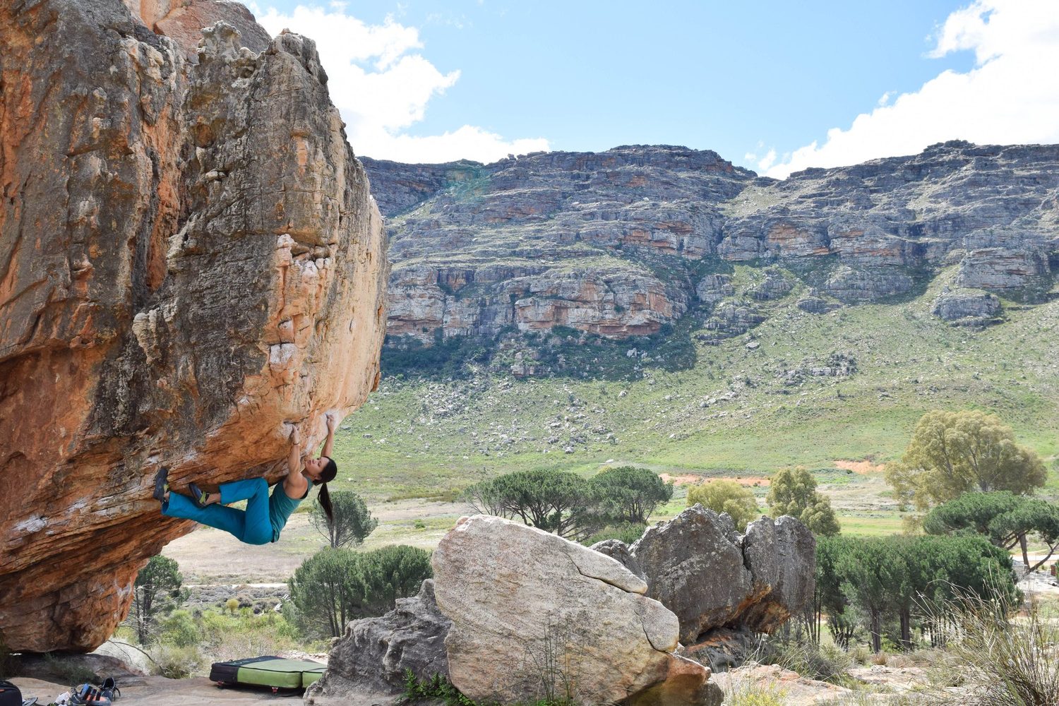 A climber topping out an orange sandstone boulder on a clear, cold Cederberg winter day